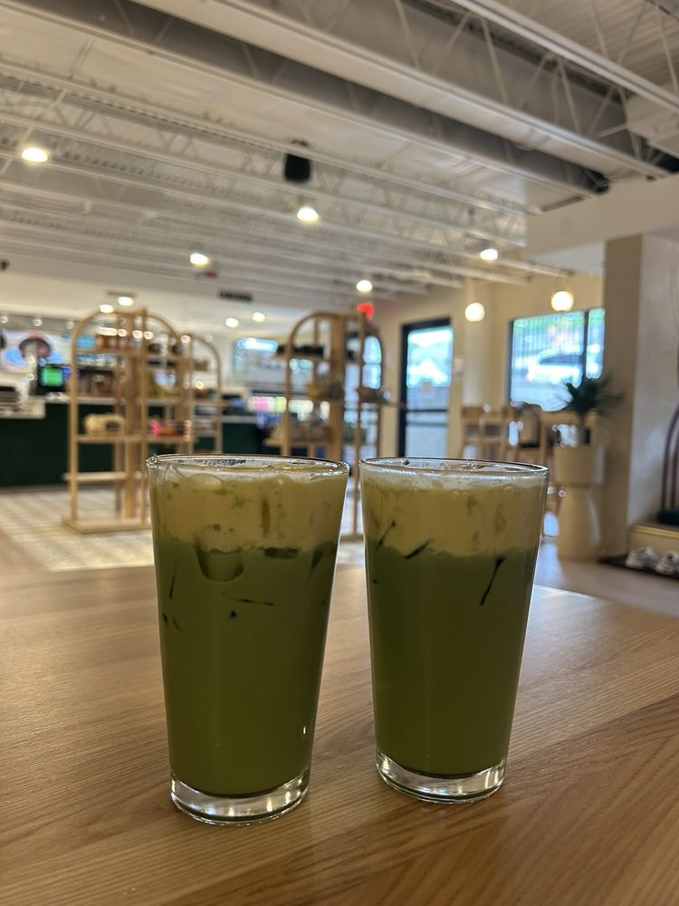Two iced matcha lattes on a wood table inside Cube Coffee