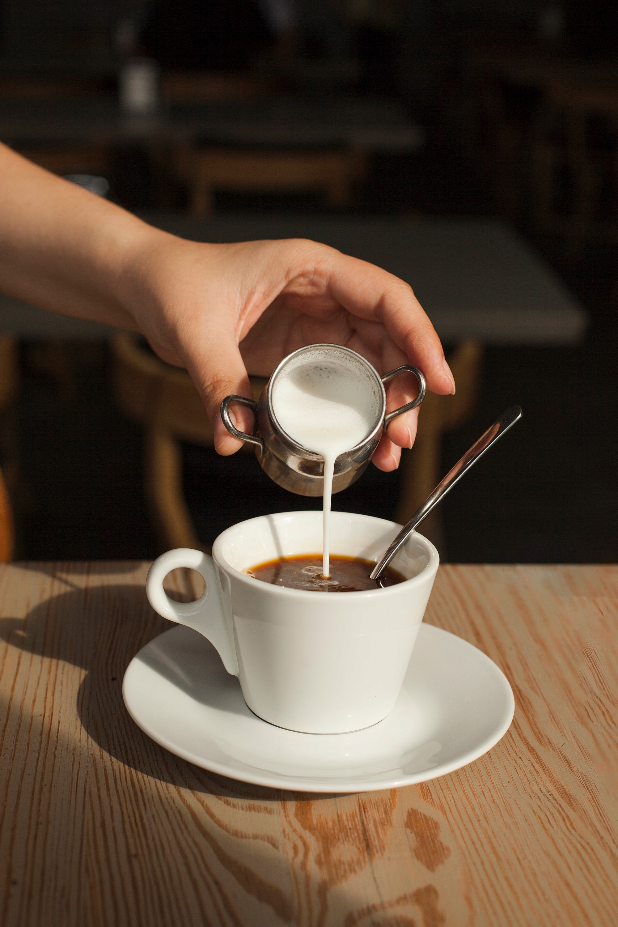 Milk being poured into black coffee